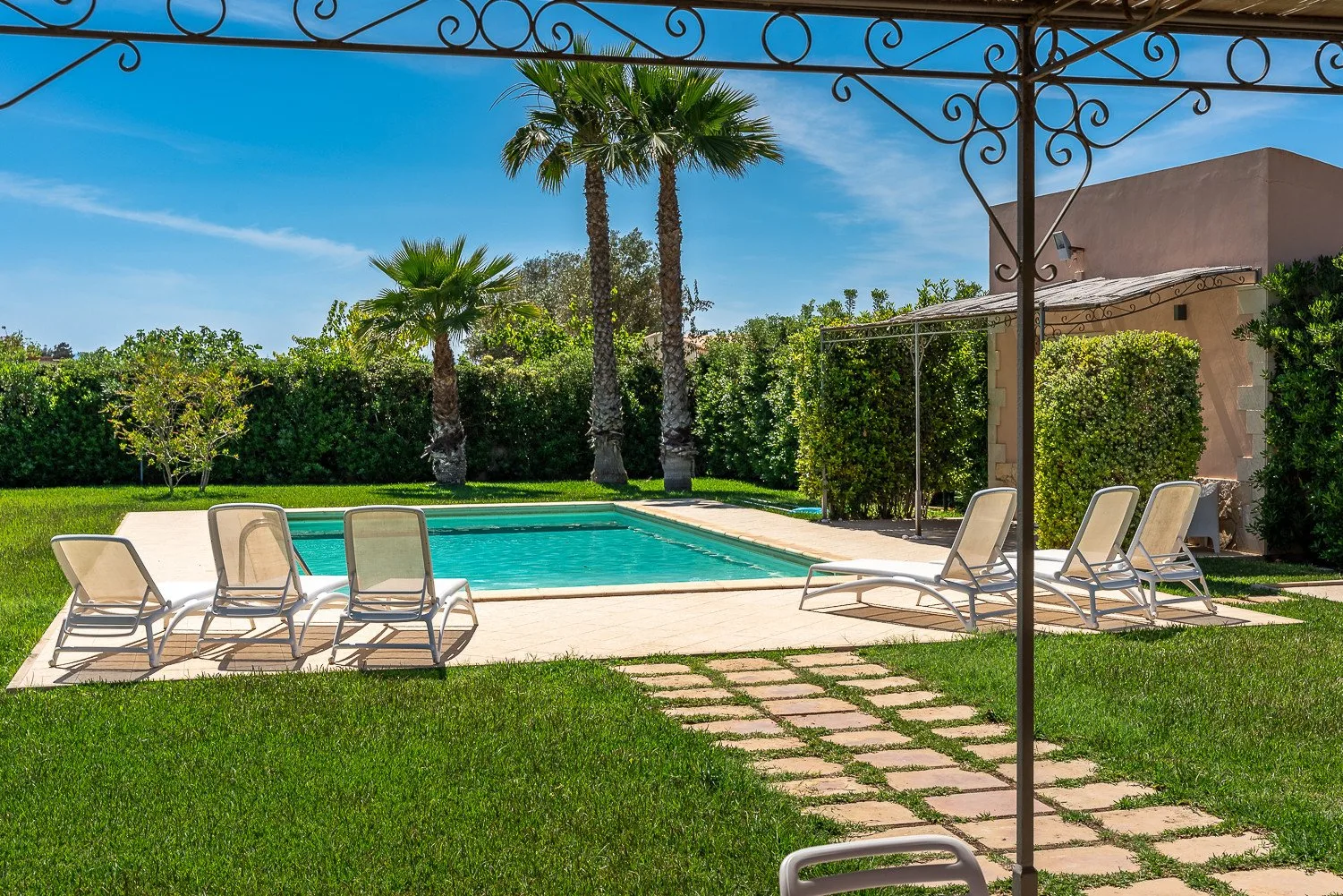 Una piscina al aire libre rodeada de asientos, vegetación y palmeras.
