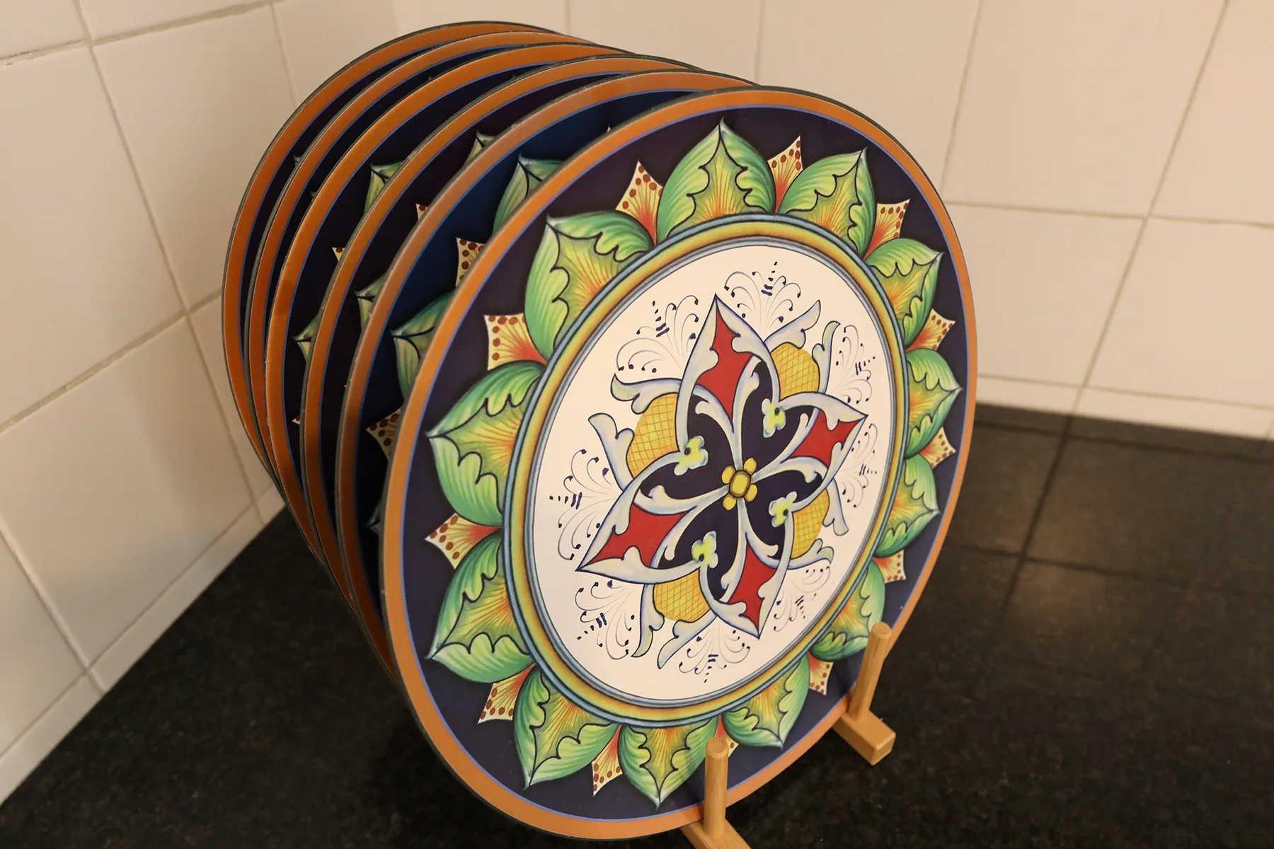 Platos decorativos con motivos estampados se exhiben en un soporte junto a una pared alicatada.