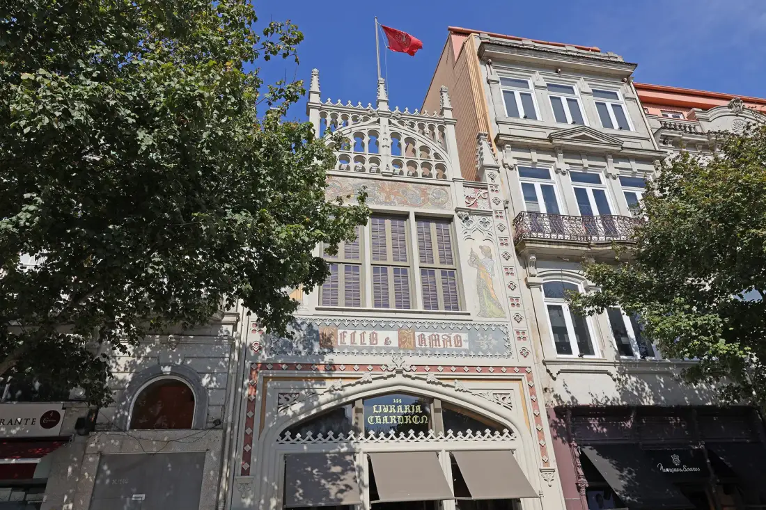 Fachada decorada de un edificio con ventanas arqueadas y una bandera roja sobre la entrada.