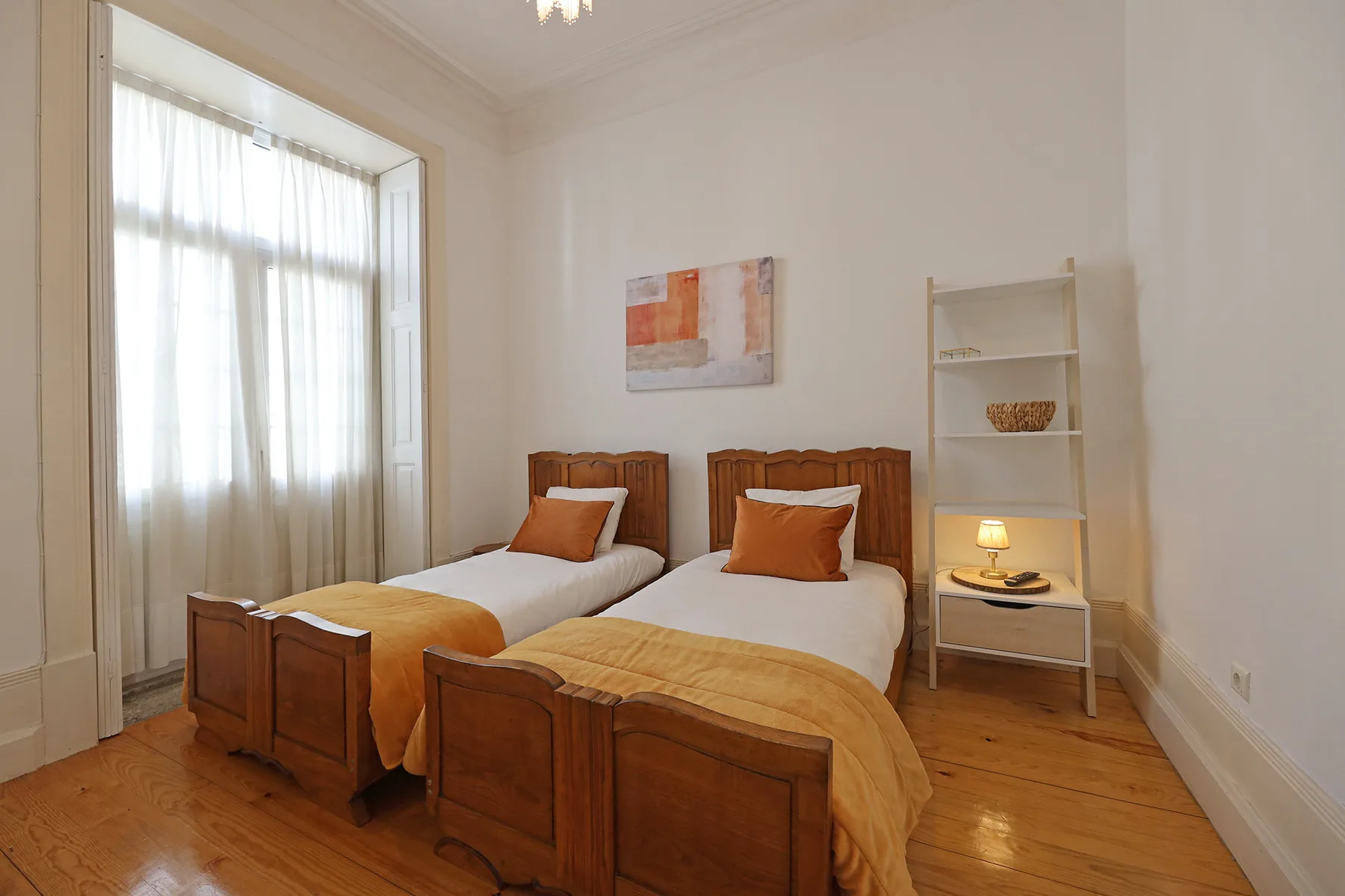 Un dormitorio con dos camas y una ventana alta.