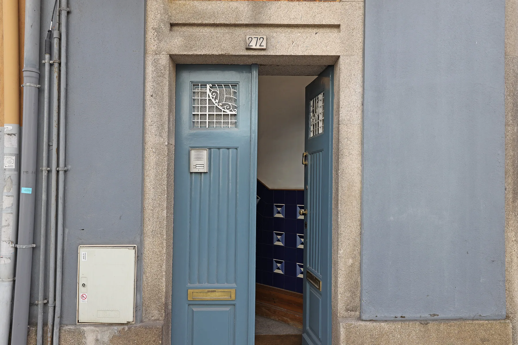 Una puerta azul abierta da a un pasillo interior.