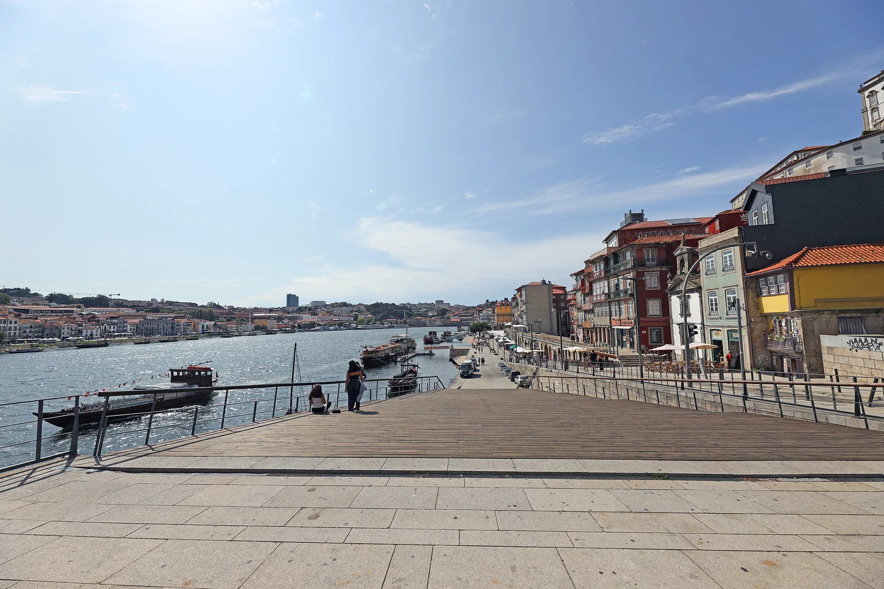 Un paseo junto al río ofrece una amplia vista del agua, con barcos y edificios.