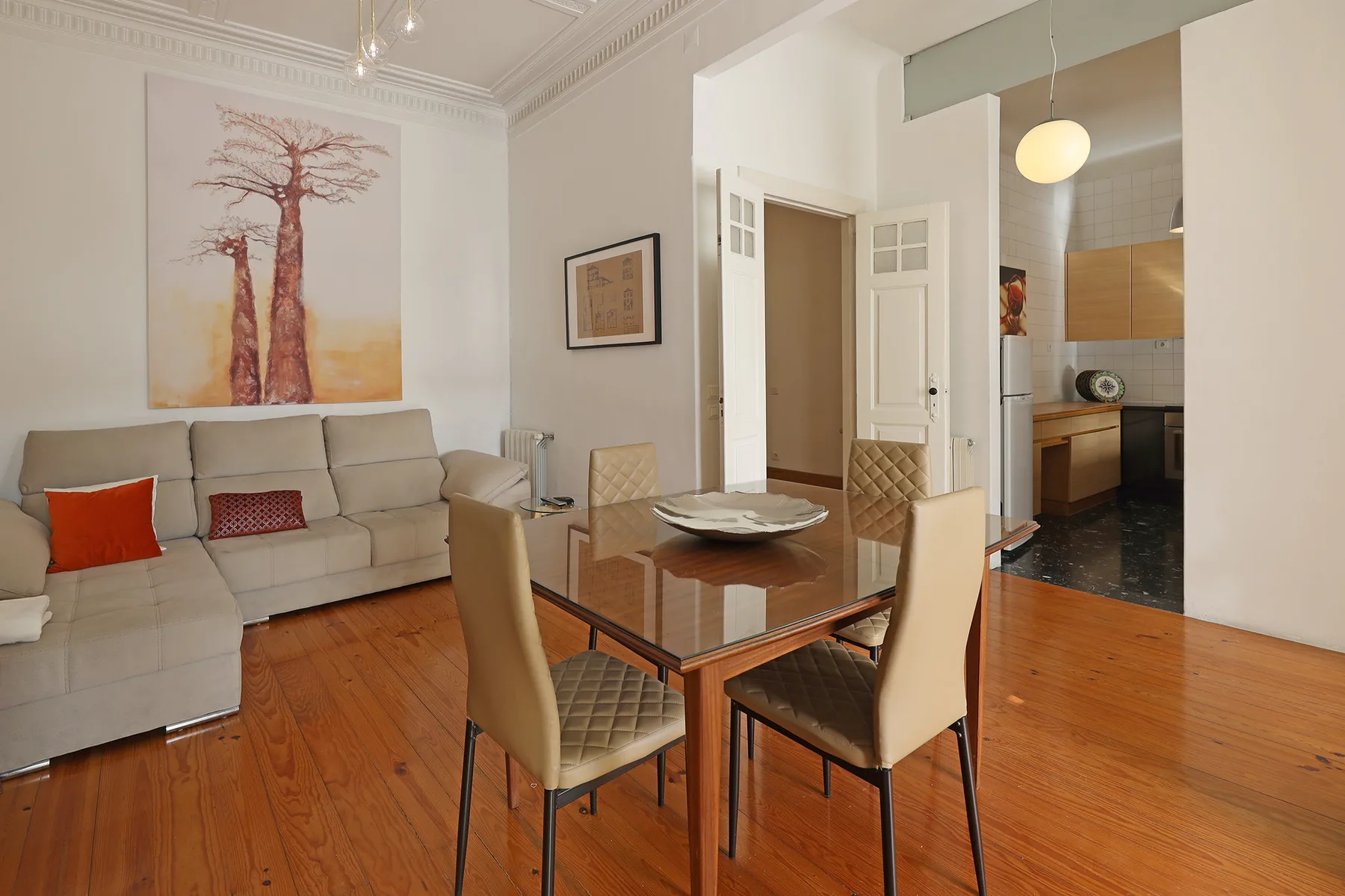 A dining area with a glass table and seating beside a living room.