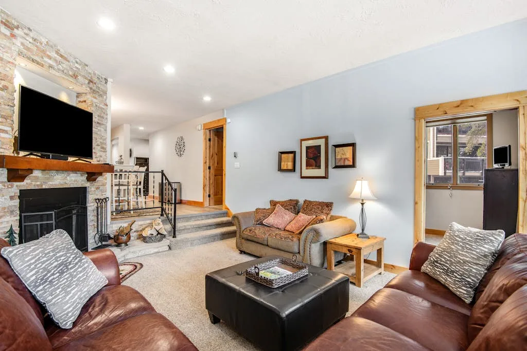 A living room with seating arranged around a coffee table and fireplace.