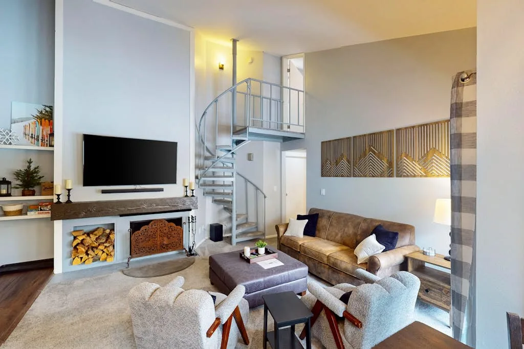Una sala de estar con asientos, un televisor y una escalera de caracol.