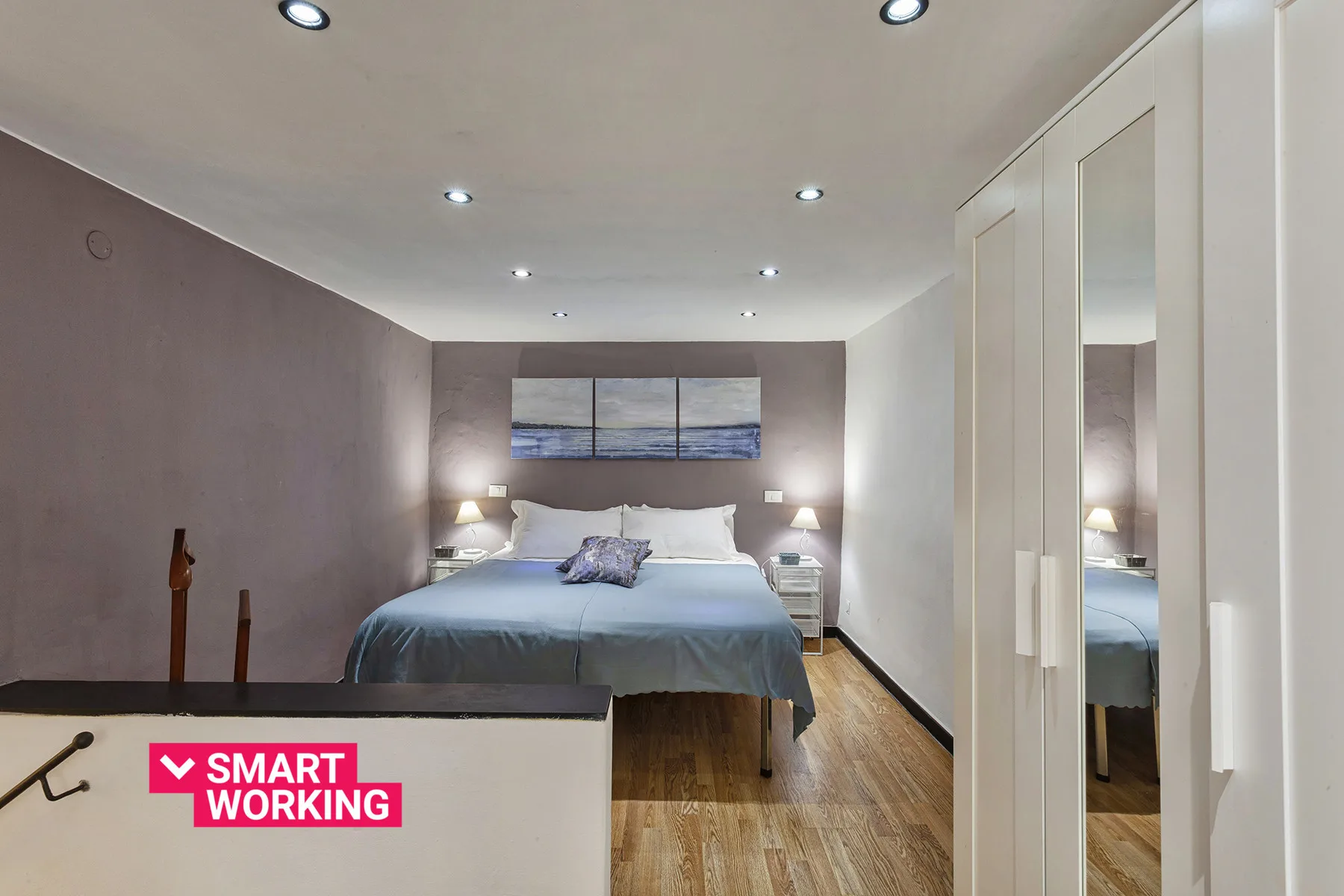 Un dormitorio con una cama bajo una ventana amplia y armarios empotrados.