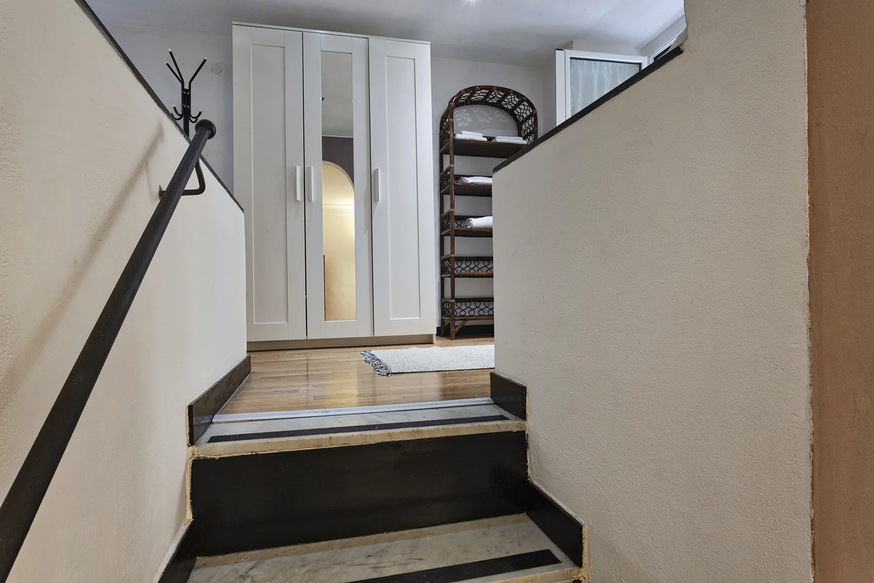 Una escalera interior corta conduce a un rellano con un armario blanco y estantes.