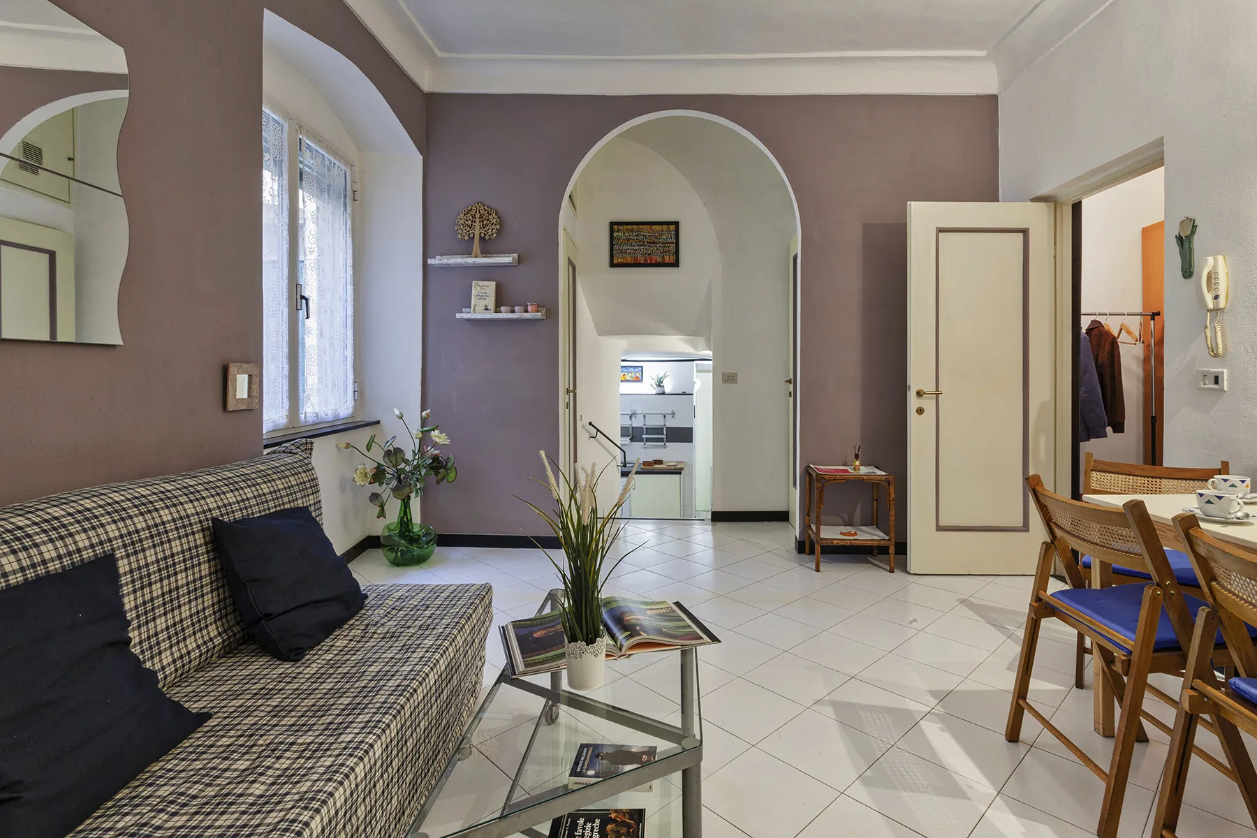 Sala de estar con asientos, una mesa de centro de vidrio y una puerta en arco.