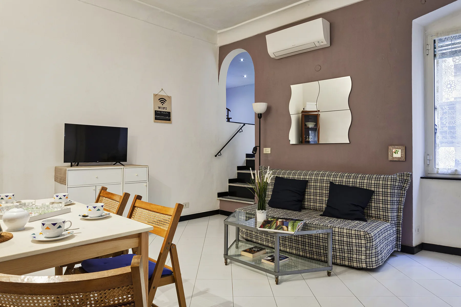 Sala de estar con asientos estampados, una mesa de centro de vidrio y un comedor.