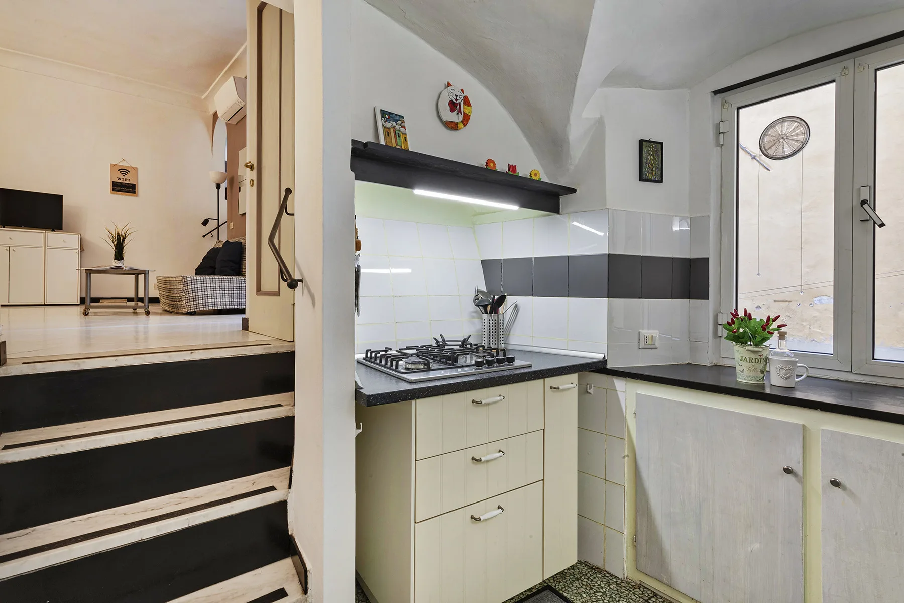 Una cocina compacta con una estufa de gas y una puerta de vidrio que da al exterior.