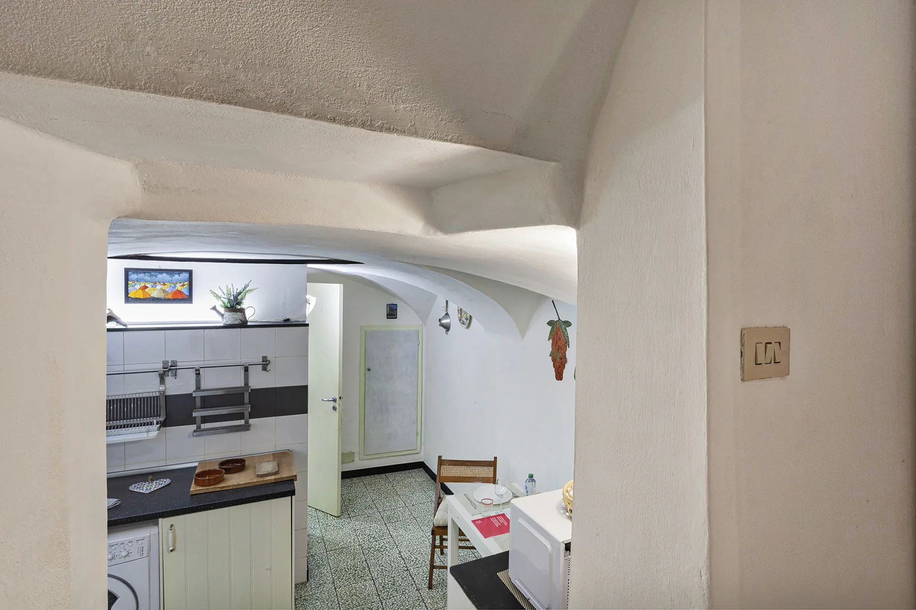Una pequeña cocina y comedor con encimeras, armarios y una mesa.