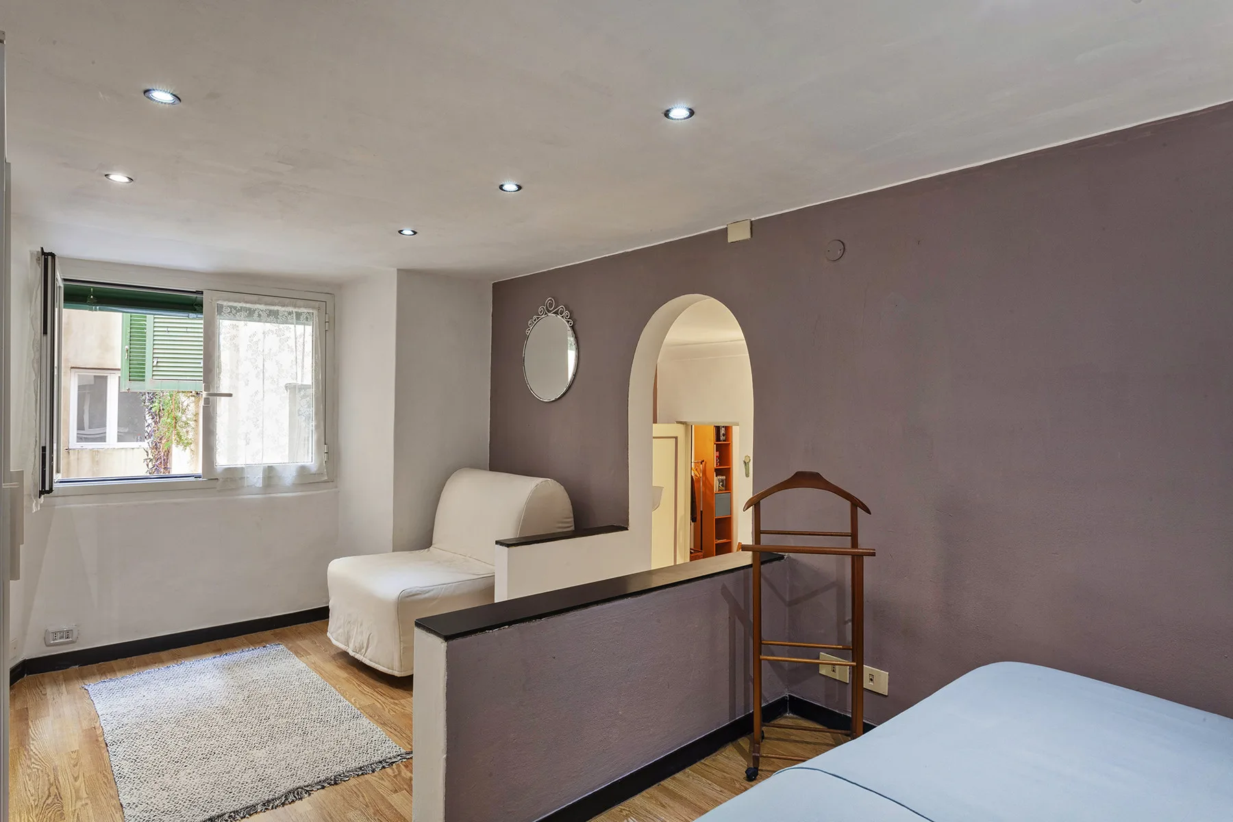 Un dormitorio con cama, zona de estar y un arco junto a una ventana.