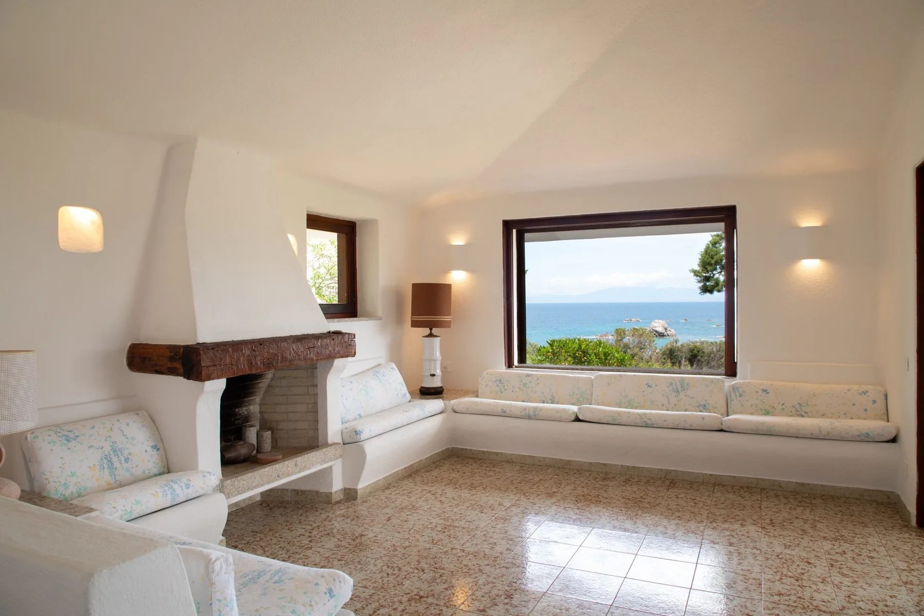 Una sala luminosa con asientos empotrados y una amplia ventana con vistas al mar.