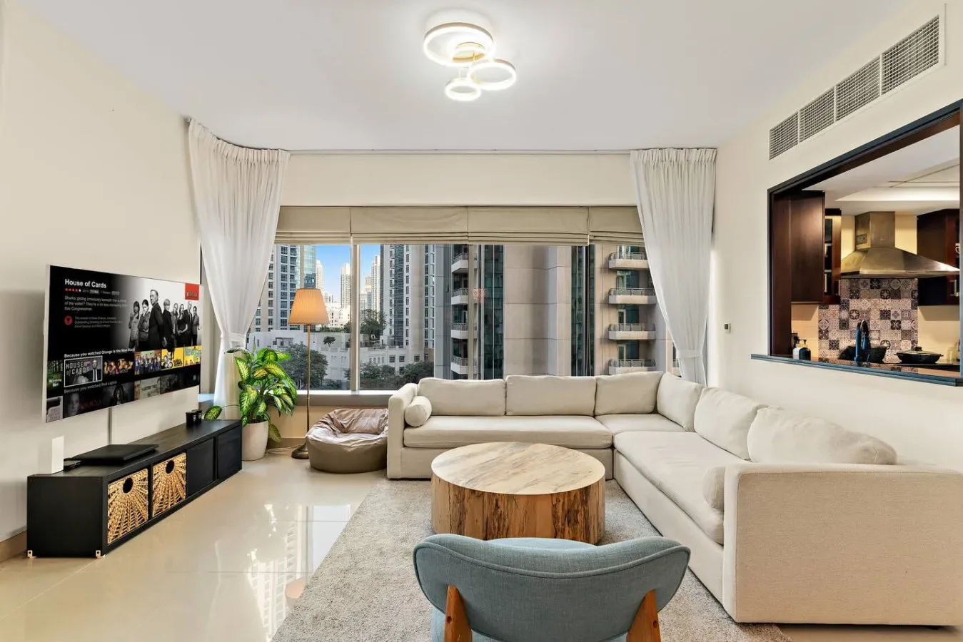A bright living room with seating, a coffee table, and large windows.