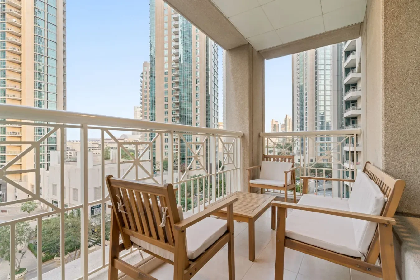 A balcony seating area with wooden furniture and views of nearby high-rise buildings.
