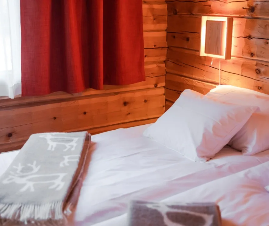 Wooden bedroom with white bedding and a reindeer-patterned blanket.