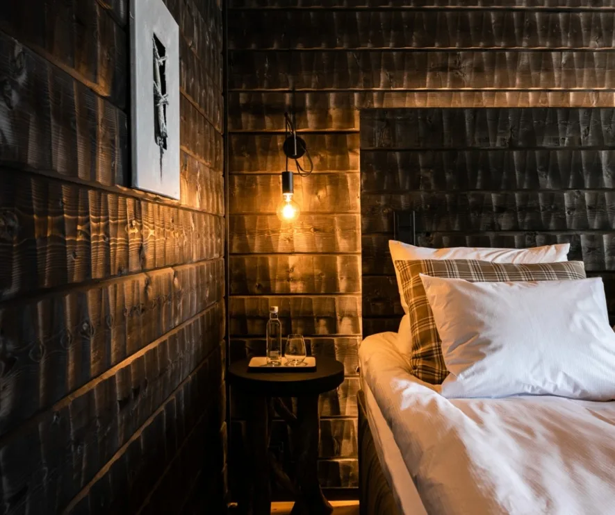 Dormitorio con paredes de madera y una mesita de noche.