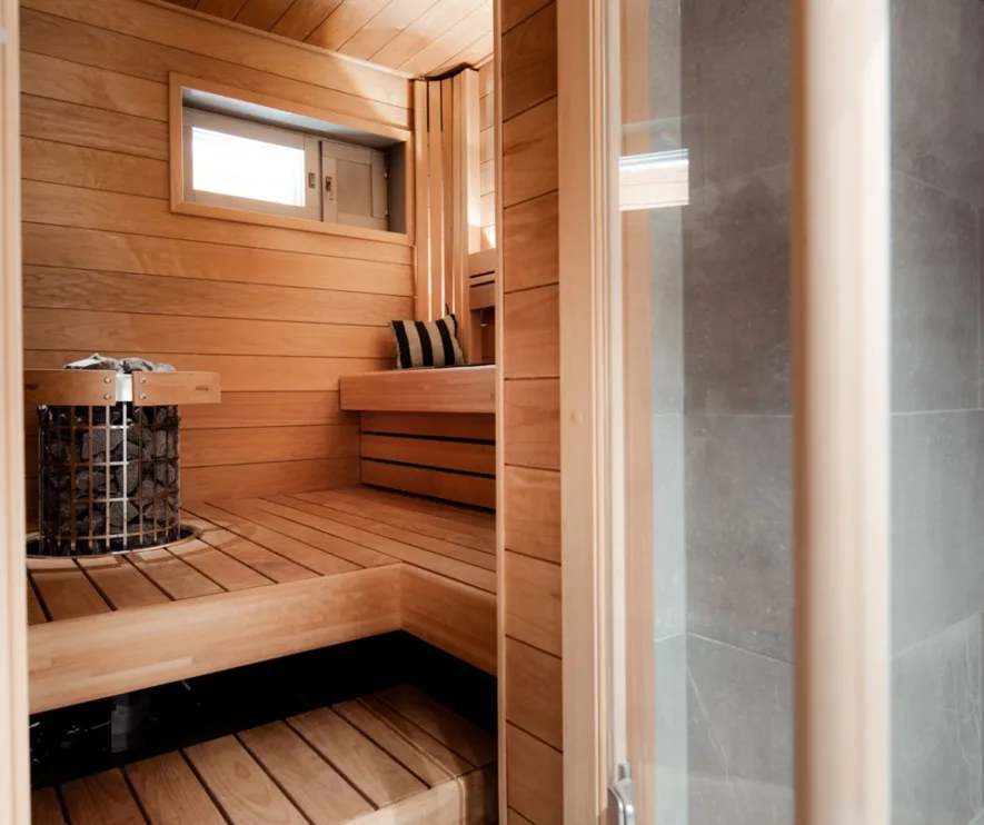 Sauna revestida de madera con bancos y una ducha.