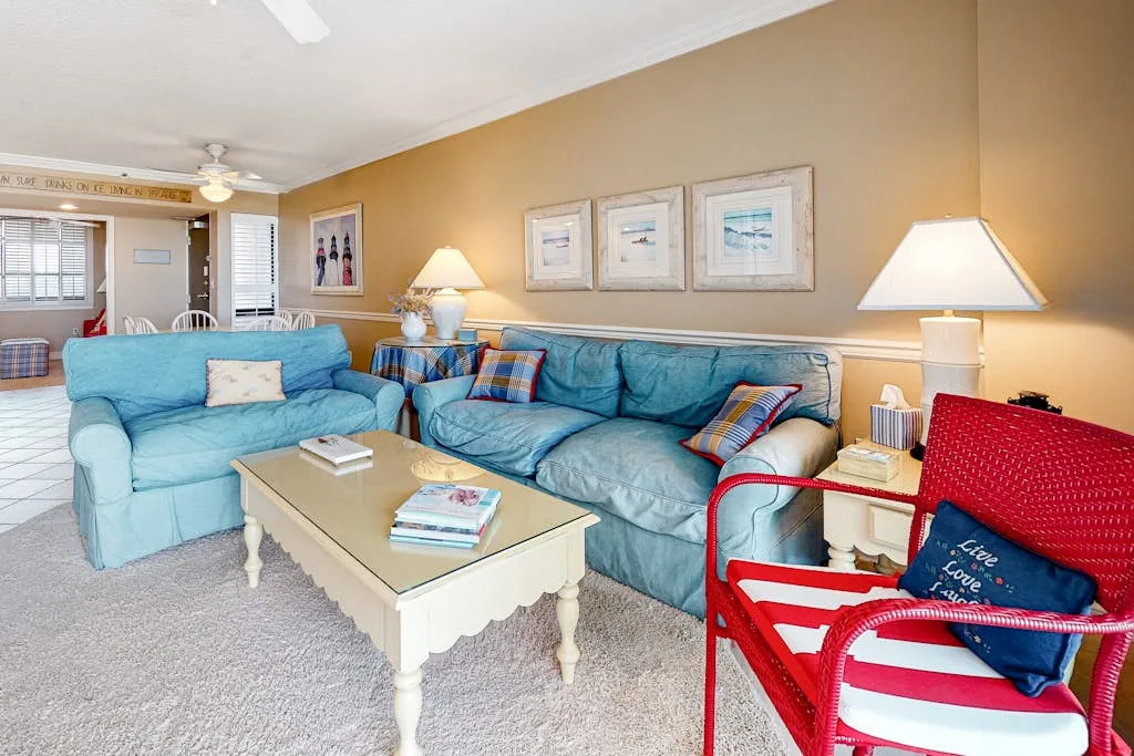 A living room with blue seating, a coffee table, and framed pictures.
