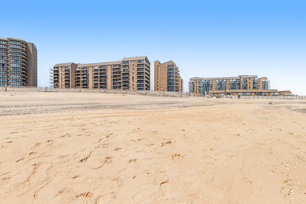 A broad sandy beach stretches toward a row of beachfront buildings.