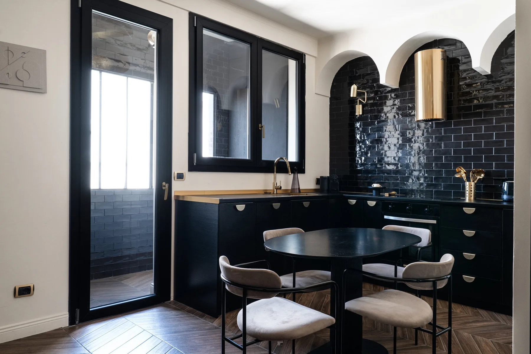 A kitchen with a dark island and a small dining table by the windows.