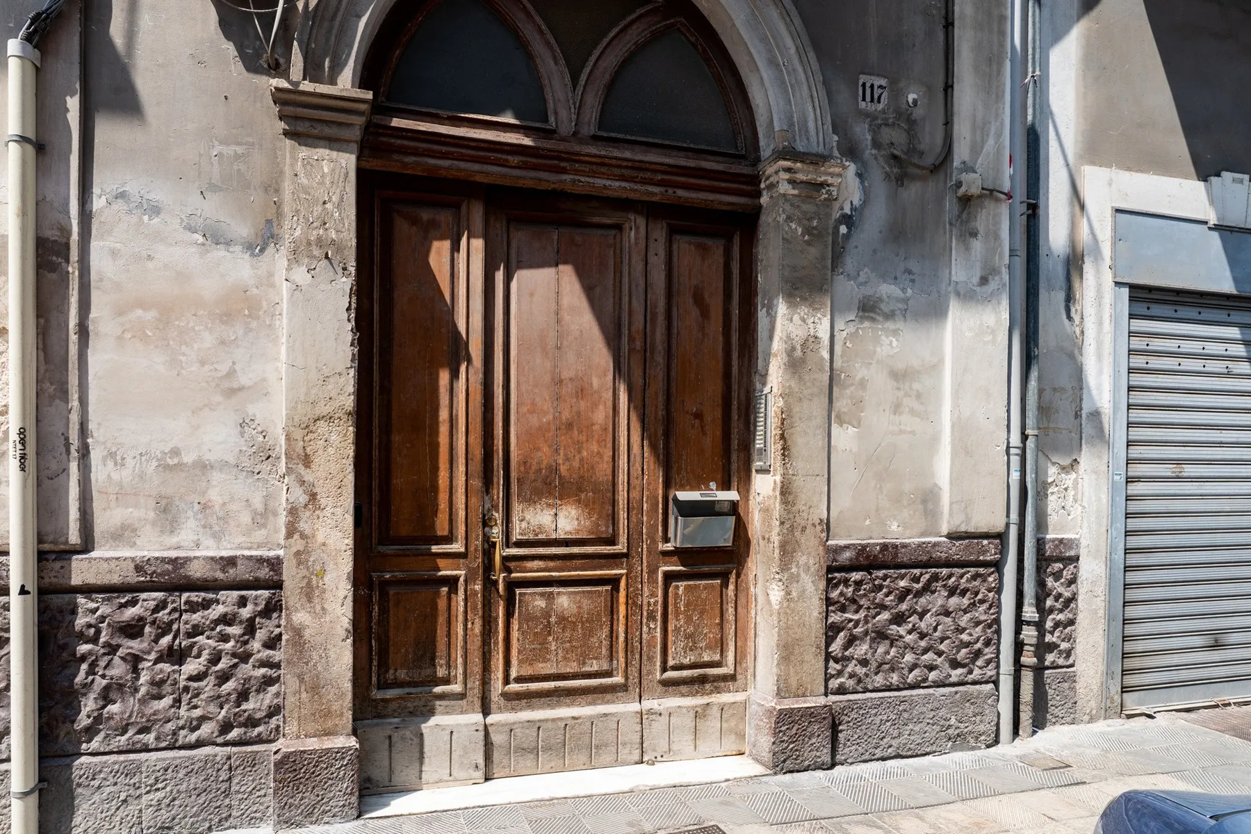 A weathered wooden entrance door is set into a stone facade.