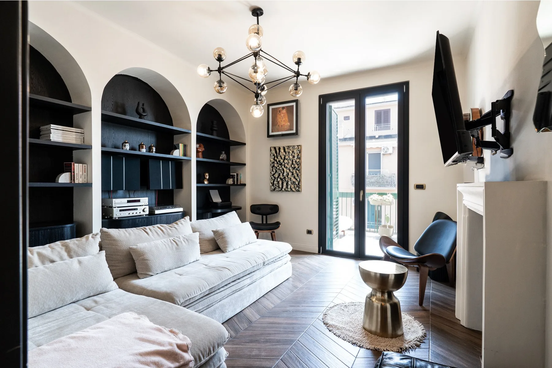 A bright living room with built-in shelving, seating, and glass doors opening to a balcony.