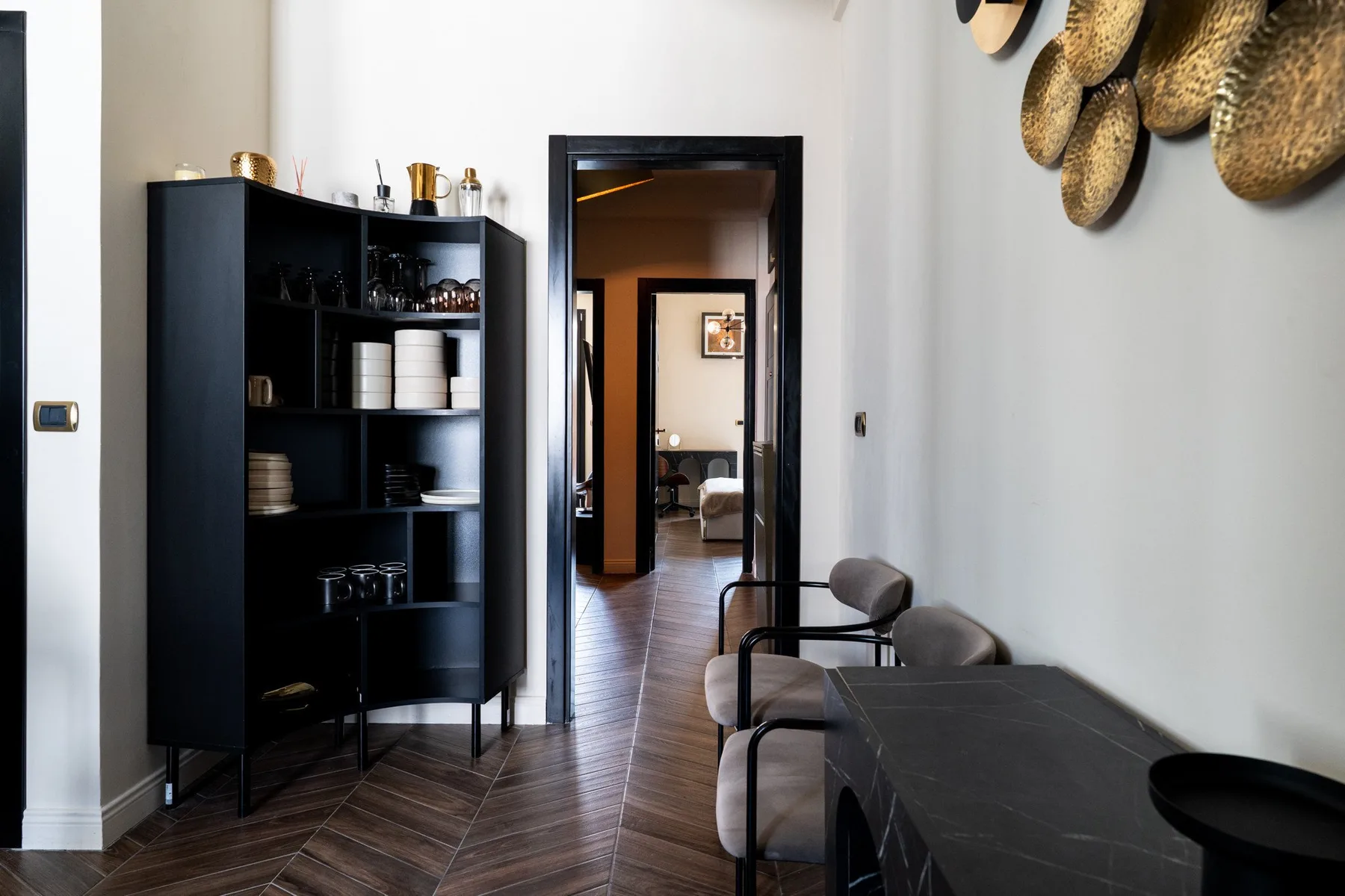 A dining area with a dark table and chairs beside a shelving unit.