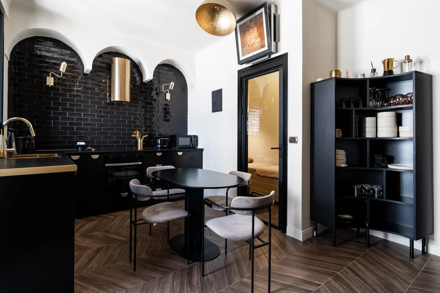 A dining area with a table and chairs beside a dark kitchen.