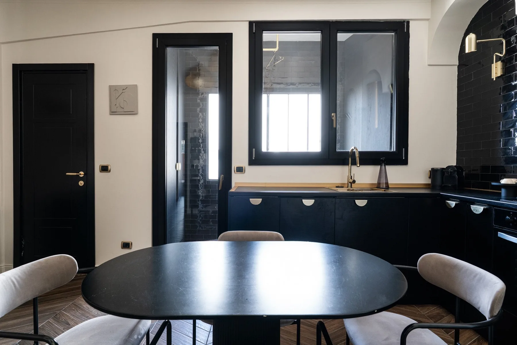 A dining area with a dark oval table and chairs beside a kitchen.