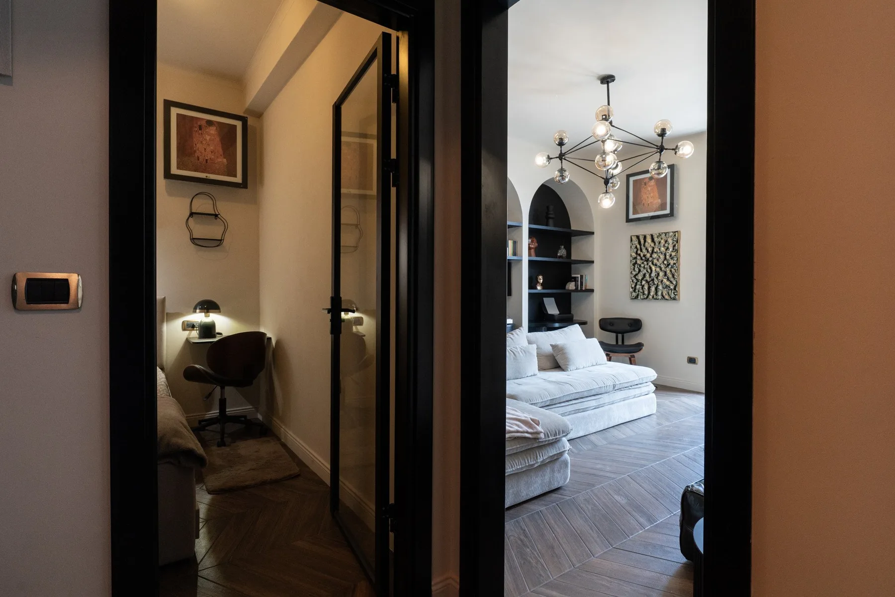 A doorway opens onto a sitting room with a chandelier and white seating.
