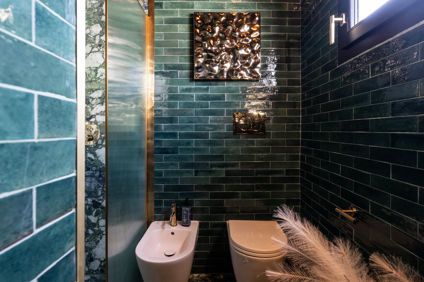 A tiled bathroom with a toilet and wall-mounted sink.