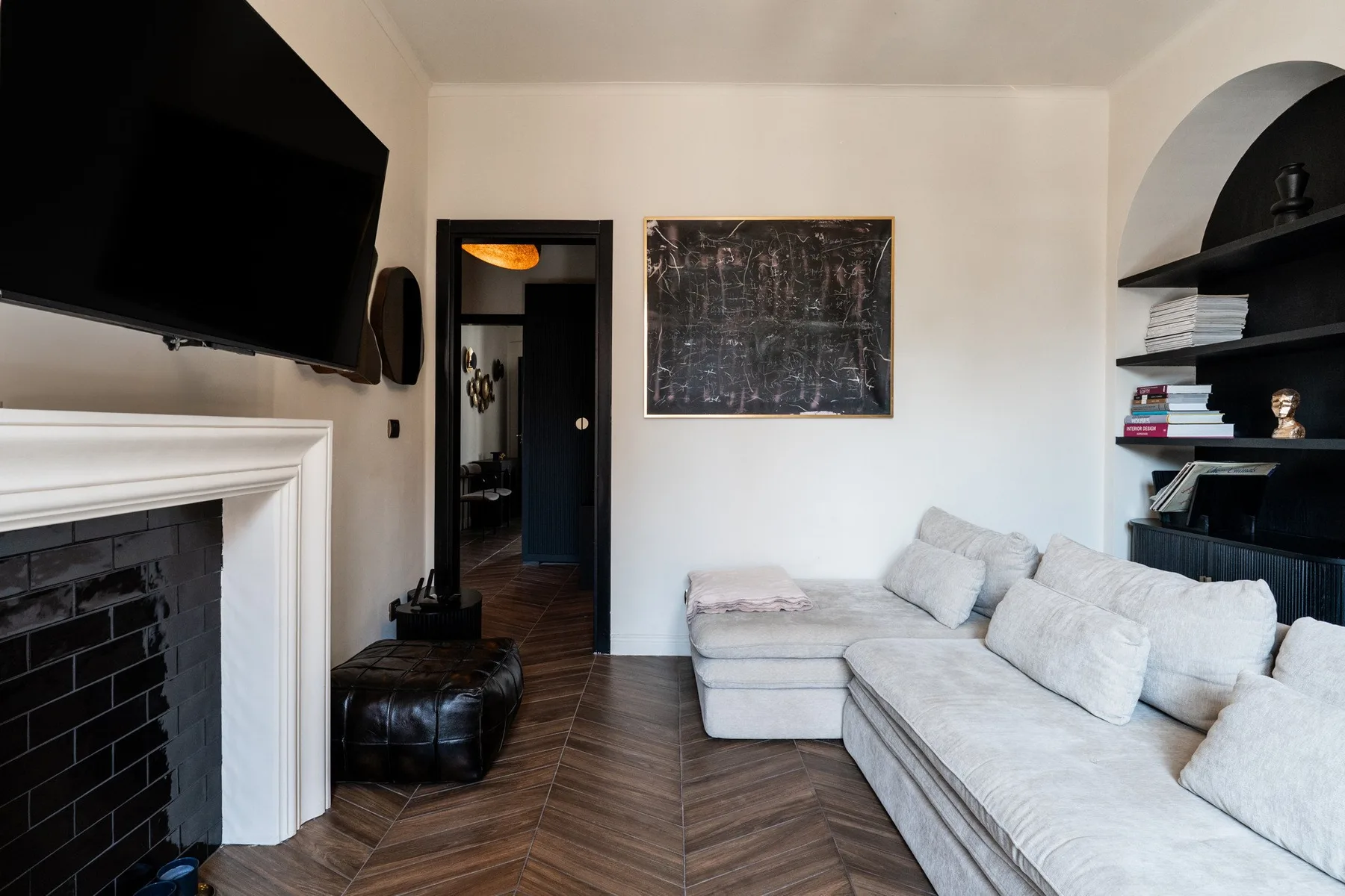 A living room with light-colored seating, a fireplace, and a wall-mounted television.