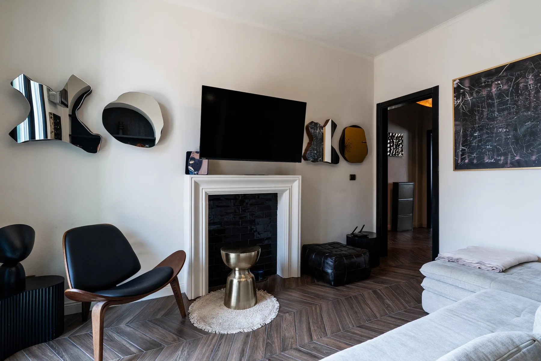 A living room with a television above the fireplace and seating nearby.