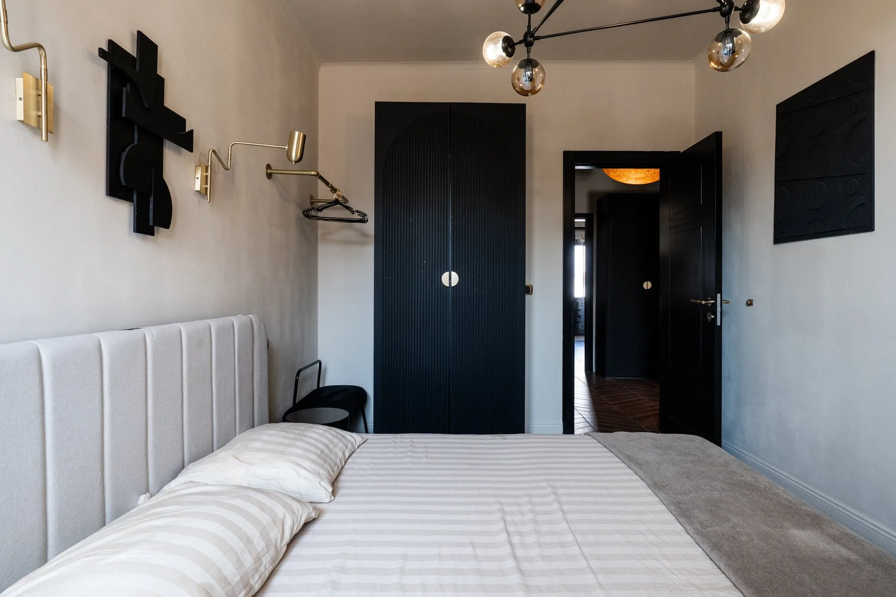 A bedroom with a neatly made bed and a dark doorway.
