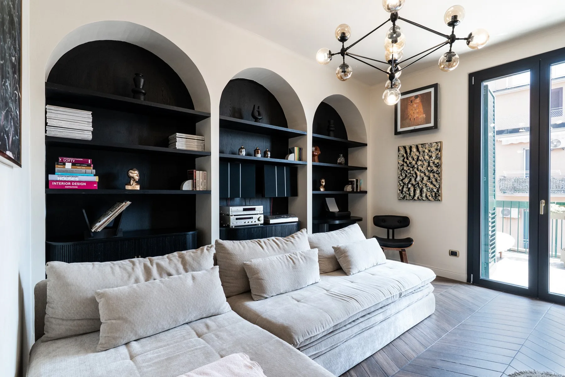 A living room with a large sectional sofa and arched built-in shelving.