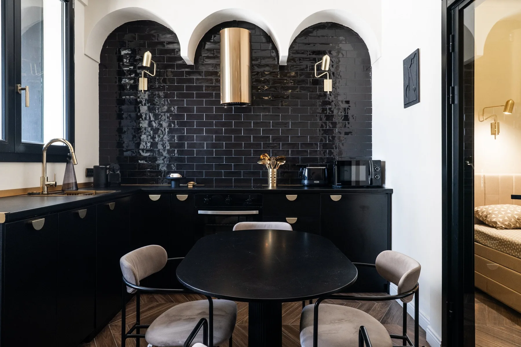 A dining area with a dark table and a black-tiled kitchen backsplash.