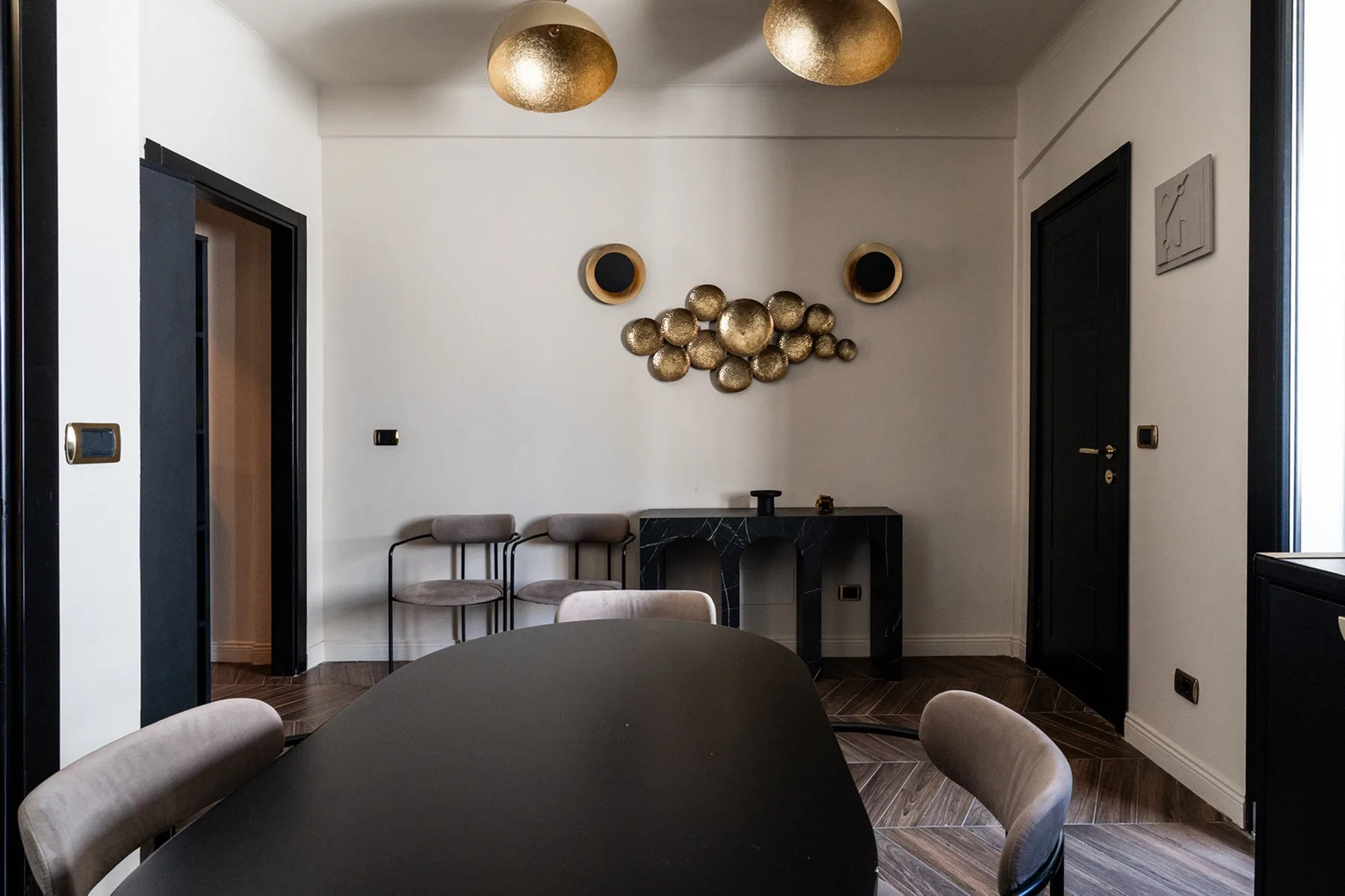 A dining area with a dark table, seating, and gold-toned wall decorations.