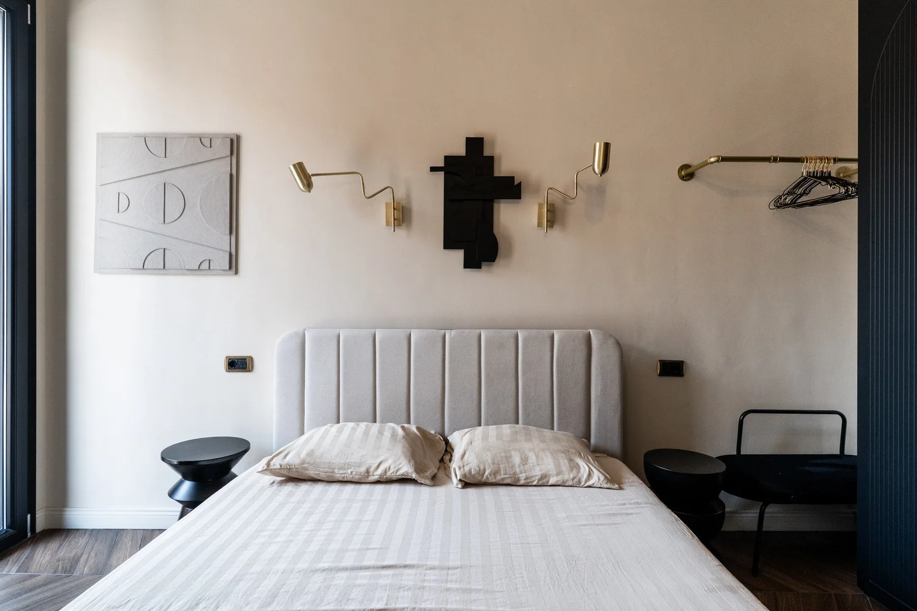A bedroom with a bed beneath a padded headboard.