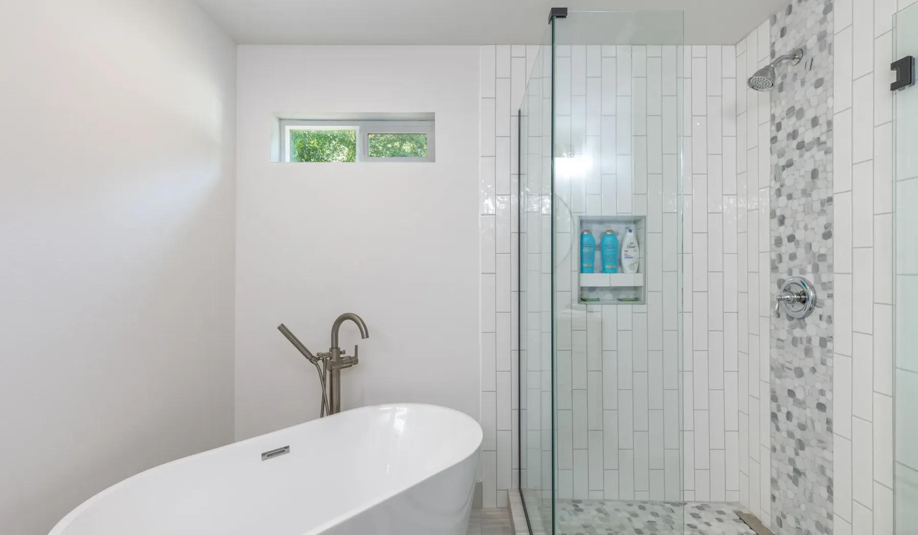 Un baño luminoso con bañera exenta y ducha con azulejos.