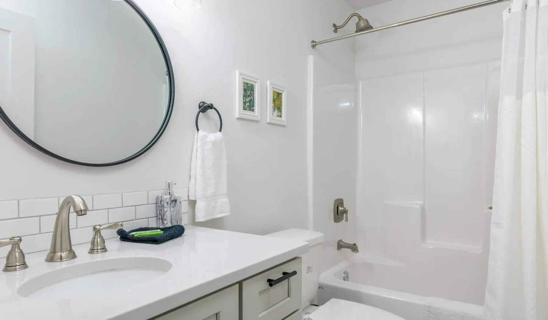 Un baño luminoso con un lavabo blanco y una bañera detrás de una cortina de ducha.