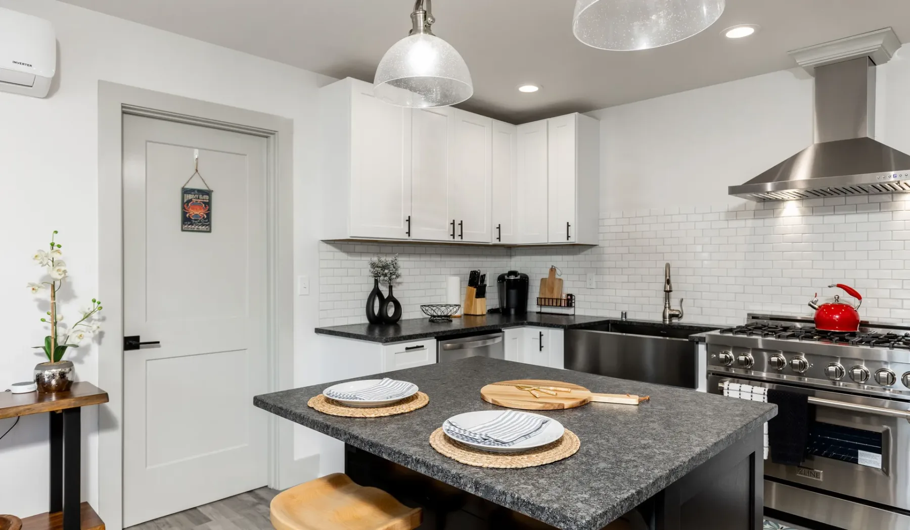 Una cocina luminosa con gabinetes blancos, una isla oscura y electrodomésticos de acero inoxidable.
