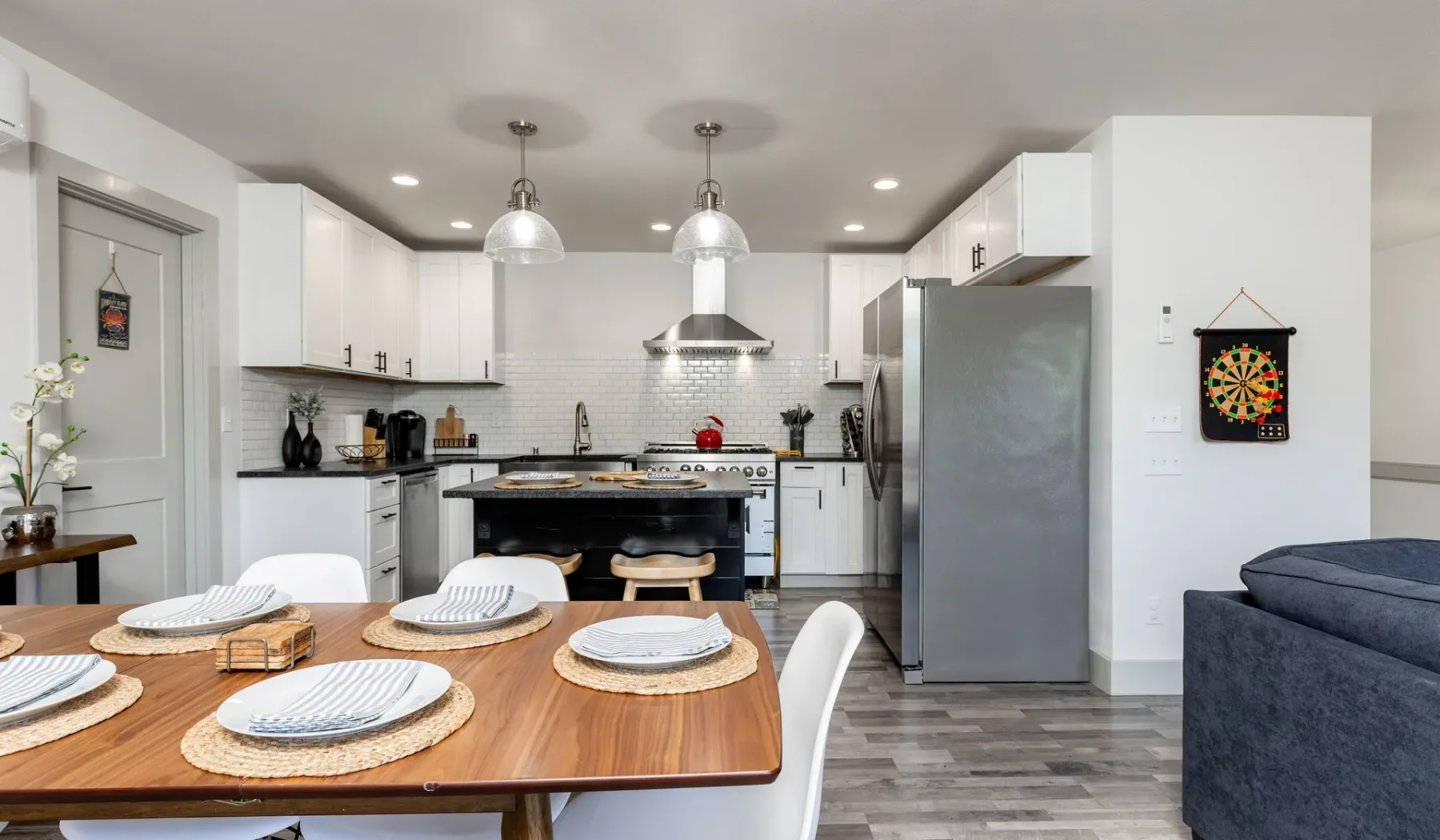 Una cocina moderna con gabinetes blancos y una mesa de comedor de madera en primer plano.