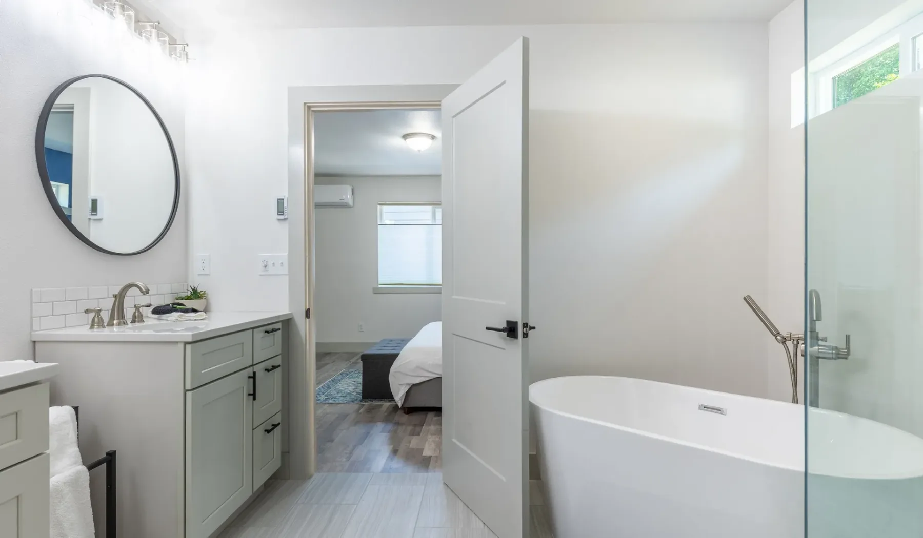 Un baño luminoso con lavabo, espejo de pared y bañera independiente.