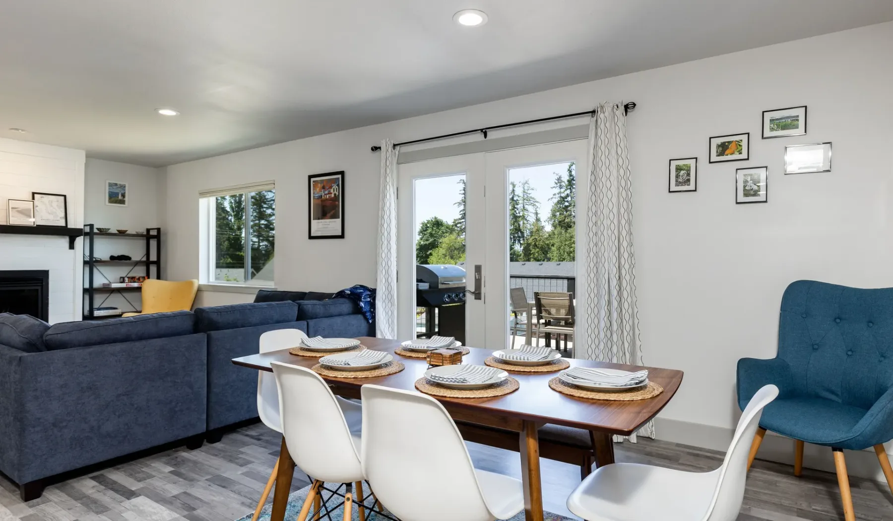 Una sala y comedor con la mesa puesta junto a puertas de vidrio que dan a un patio.