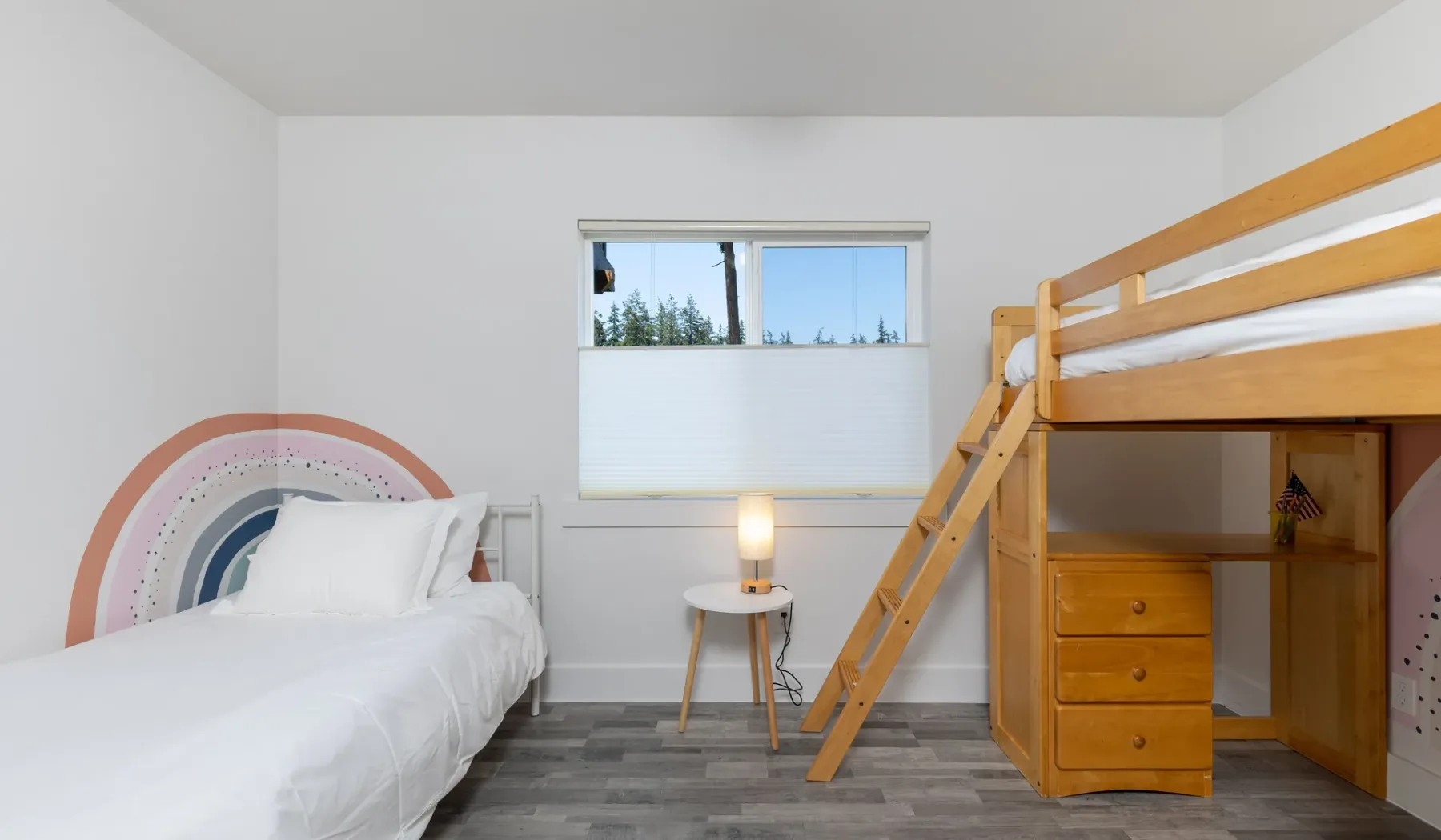 Un dormitorio luminoso con una cama y una cama alta de madera junto a la ventana.