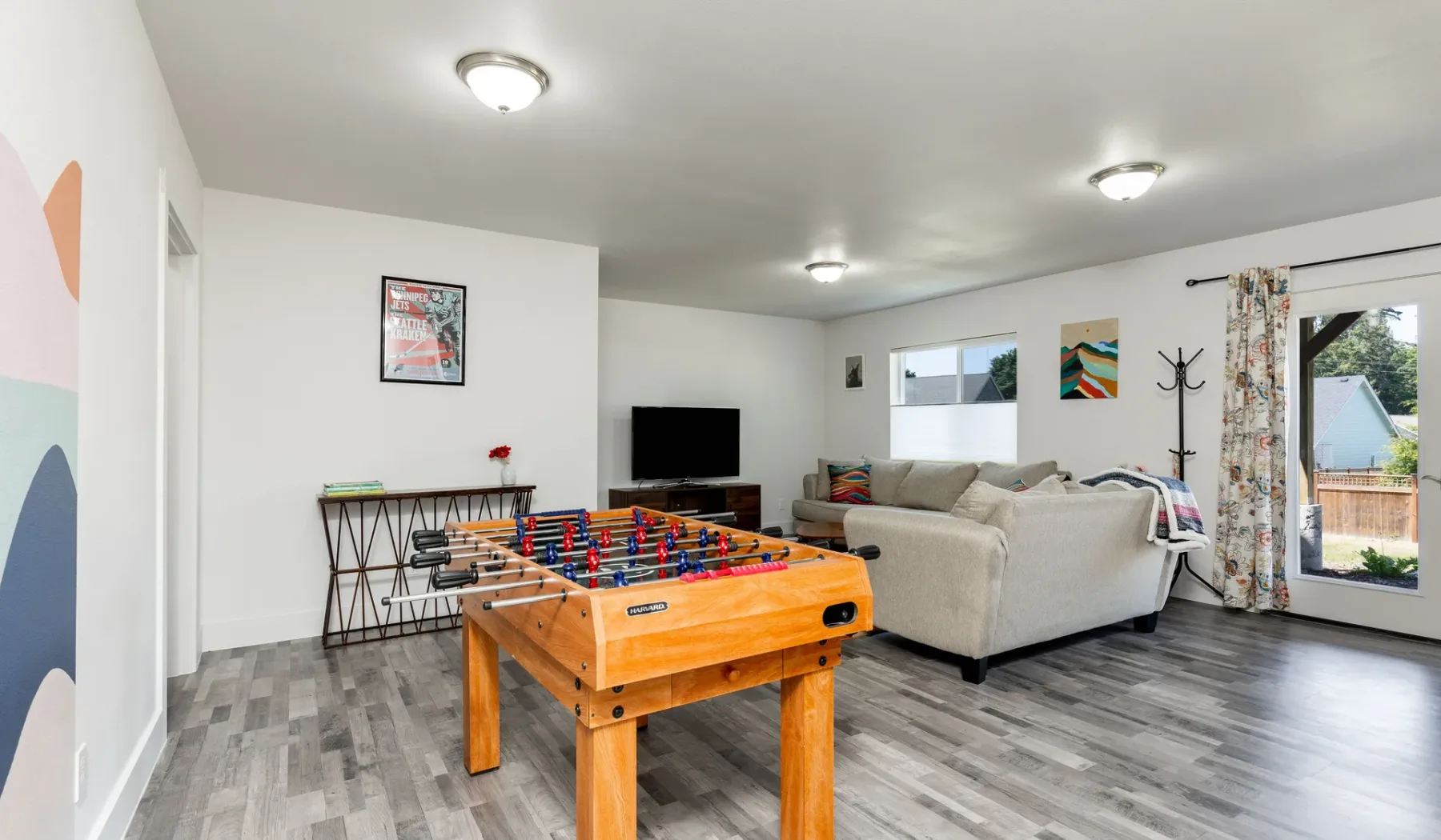 Una sala de estar con una zona de asientos, televisión y futbolín.
