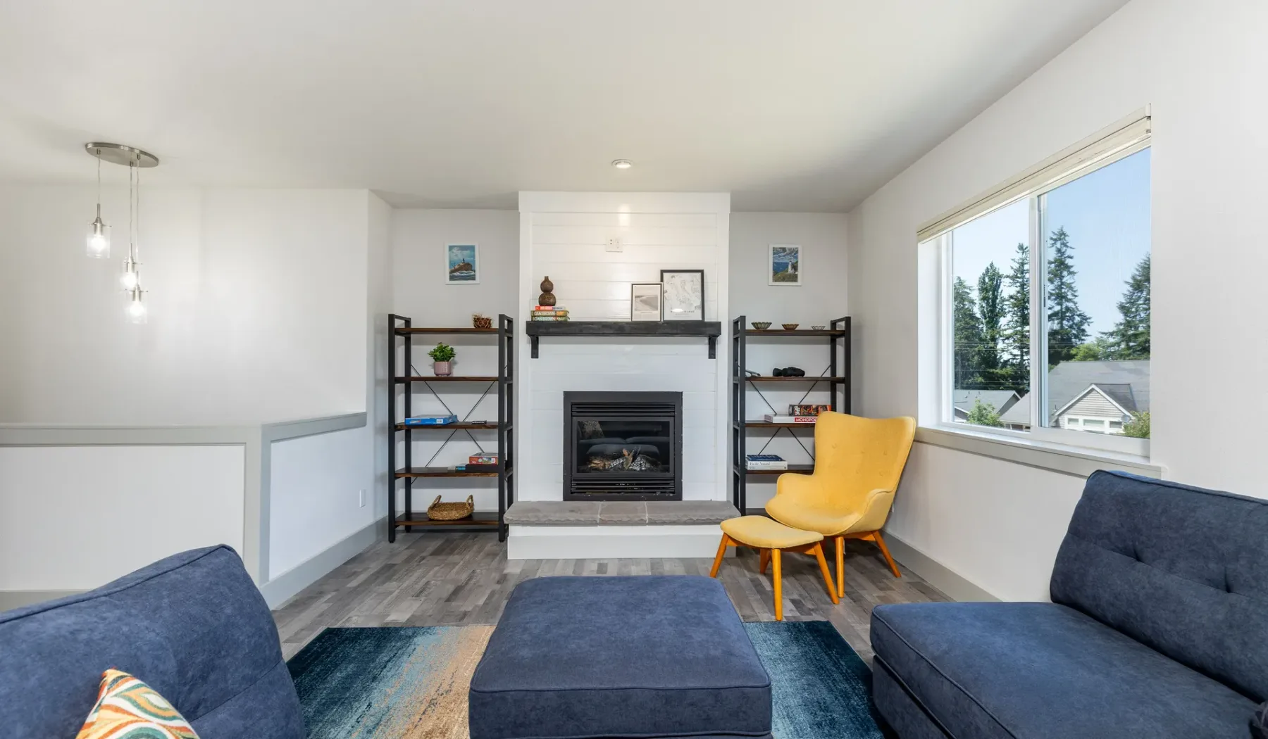 Una sala luminosa con chimenea, asientos y una ventana grande.