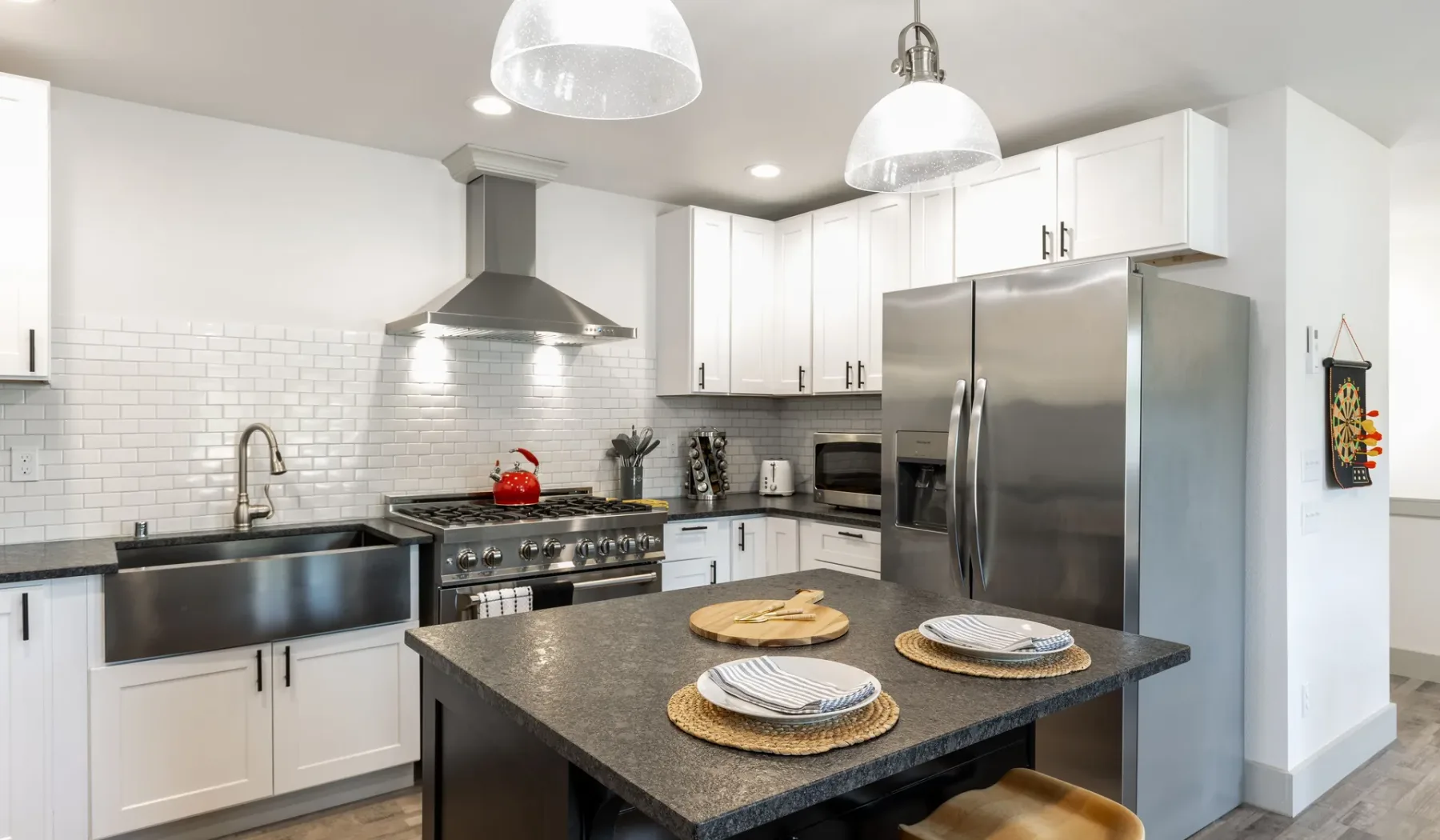 Una cocina luminosa con gabinetes blancos, electrodomésticos de acero inoxidable y una isla central.