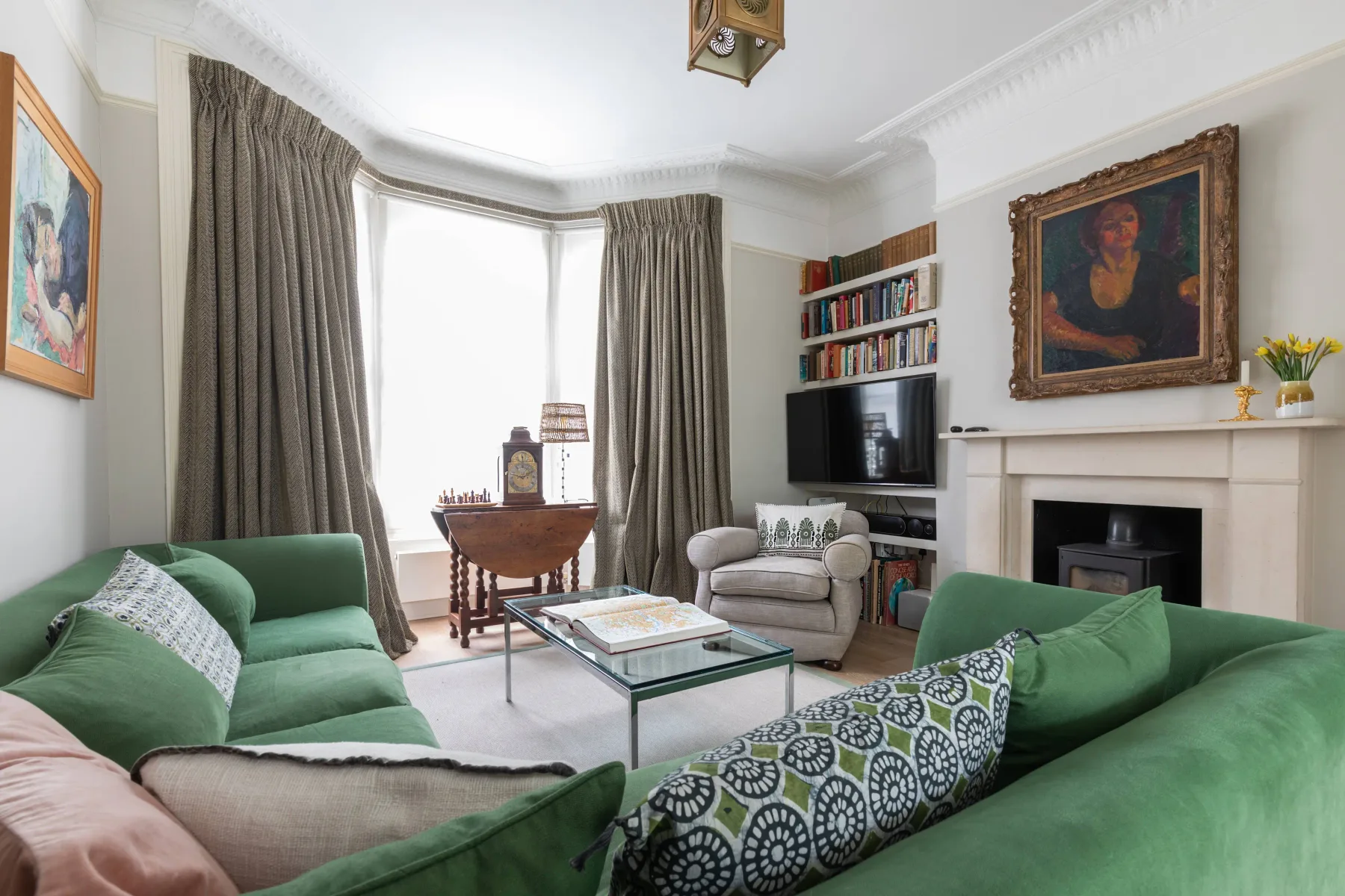 A living room with green seating, a television, and a fireplace.